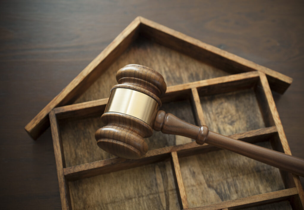 Gavel over a wooden house.